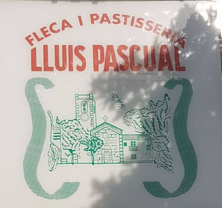 Logo clásico de la pastelería Lluís Pascual, con diseño ilustrado de una iglesia y árboles, acompañado del nombre "Fleca i Pastisseria" en letras rojas.